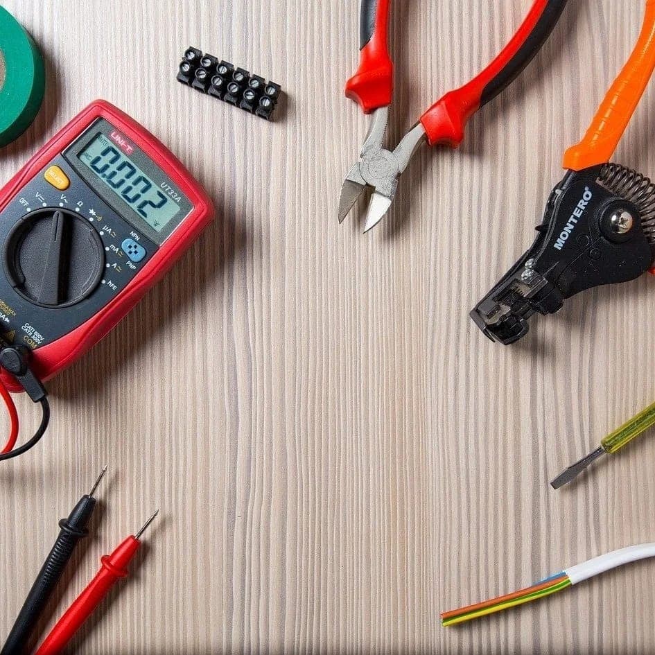 Multimeter, avbitare, skalverktyg och kopplingsplint på en träskiva